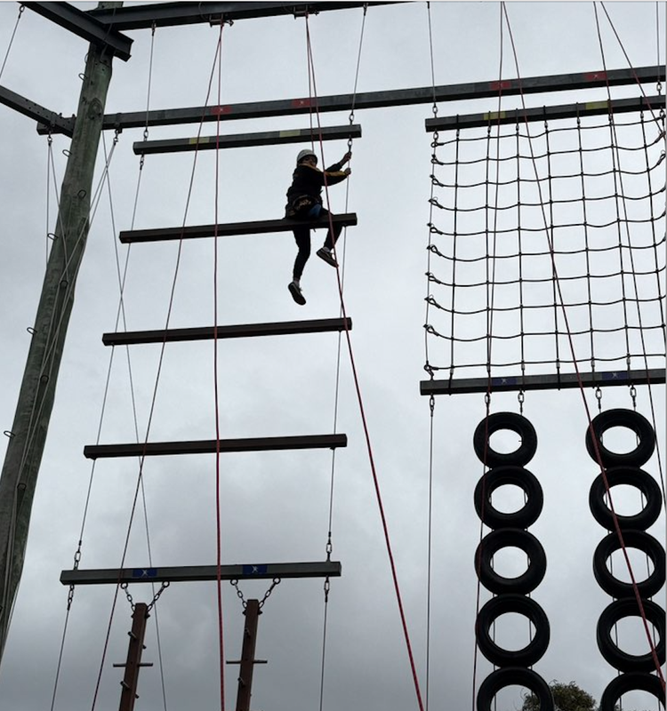 A child participating in a ropes course at camp.