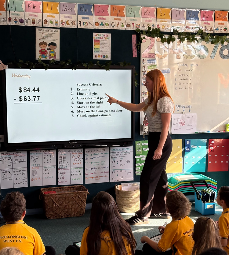 teacher pointing at a whiteboard